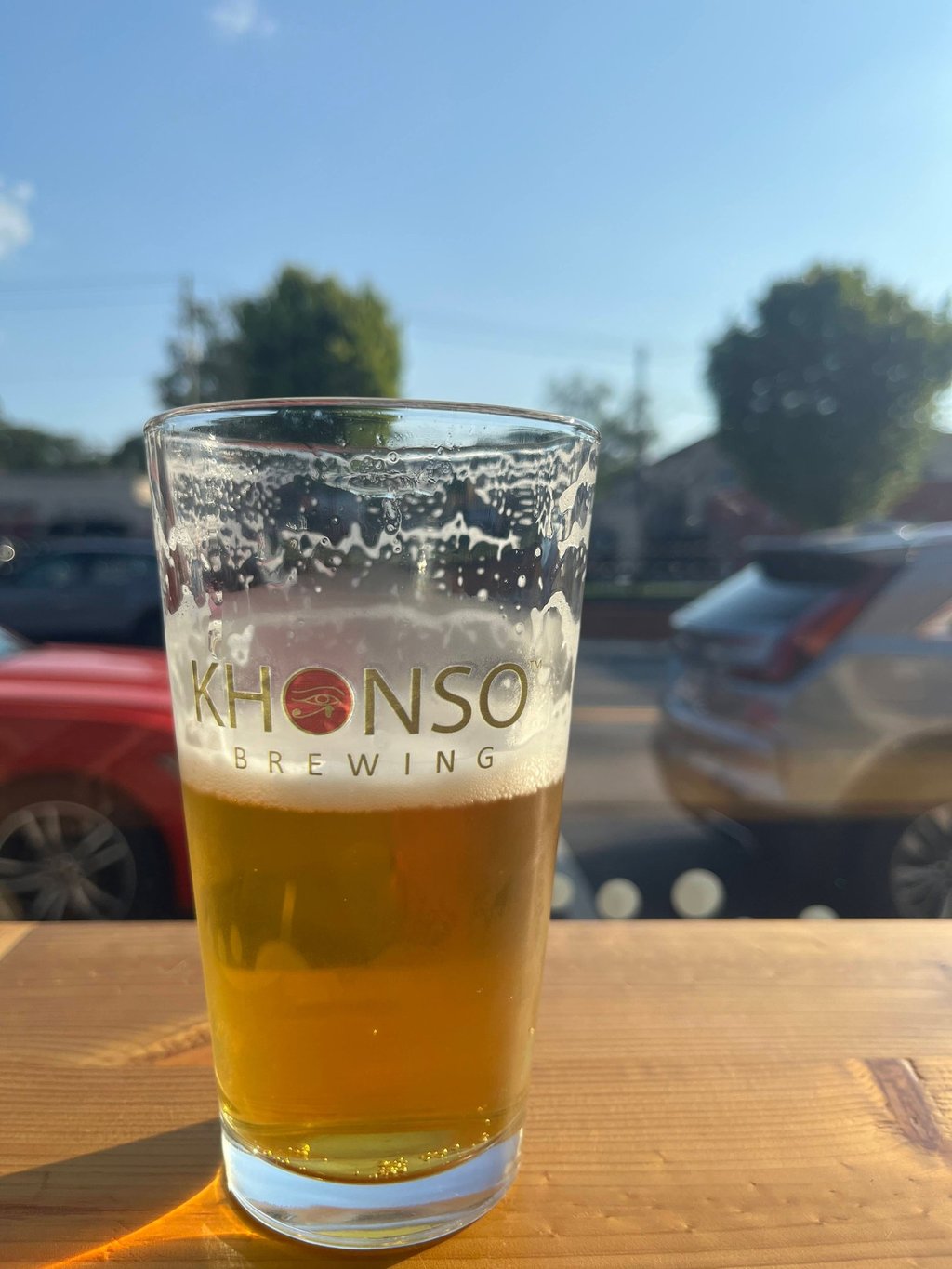 A cold pint of craft beer from Khonso Brewing sitting on a sunny outdoor patio table.