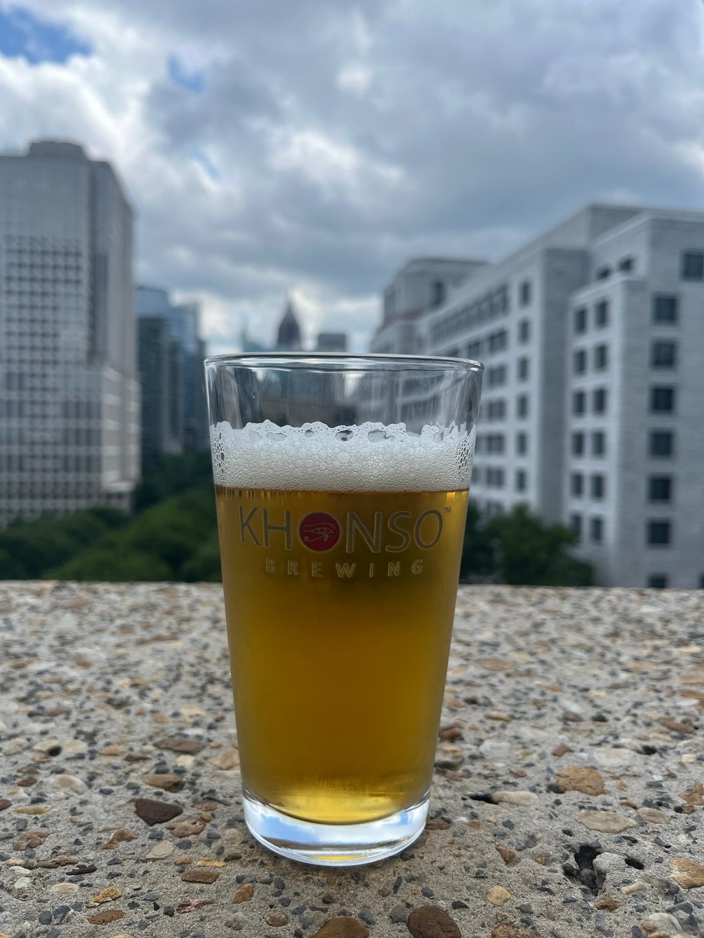 A glass of Khonso Brewing craft beer on a rooftop overlooking the Atlanta city skyline.
