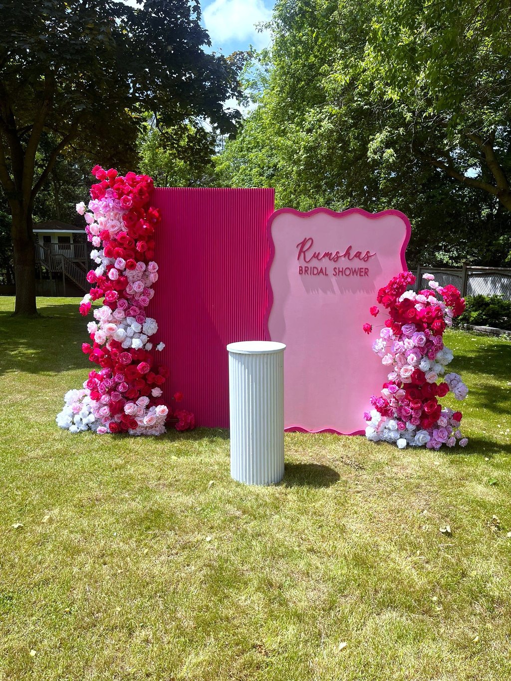 a hot pink and white floral bacldrop for a bridal shower outside