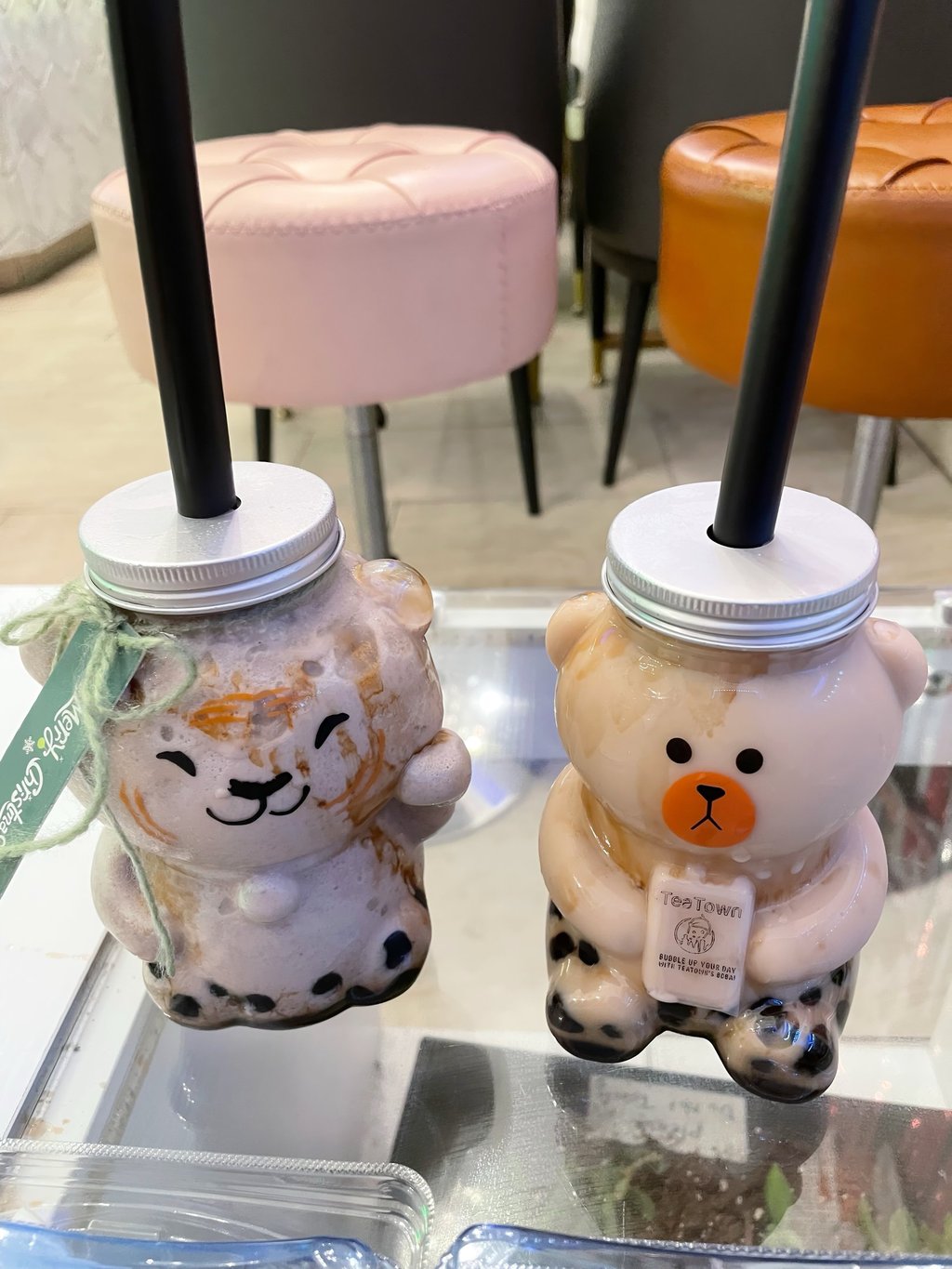 two cups of brown sugar milk tea with boba in animal-shaped cups on a table