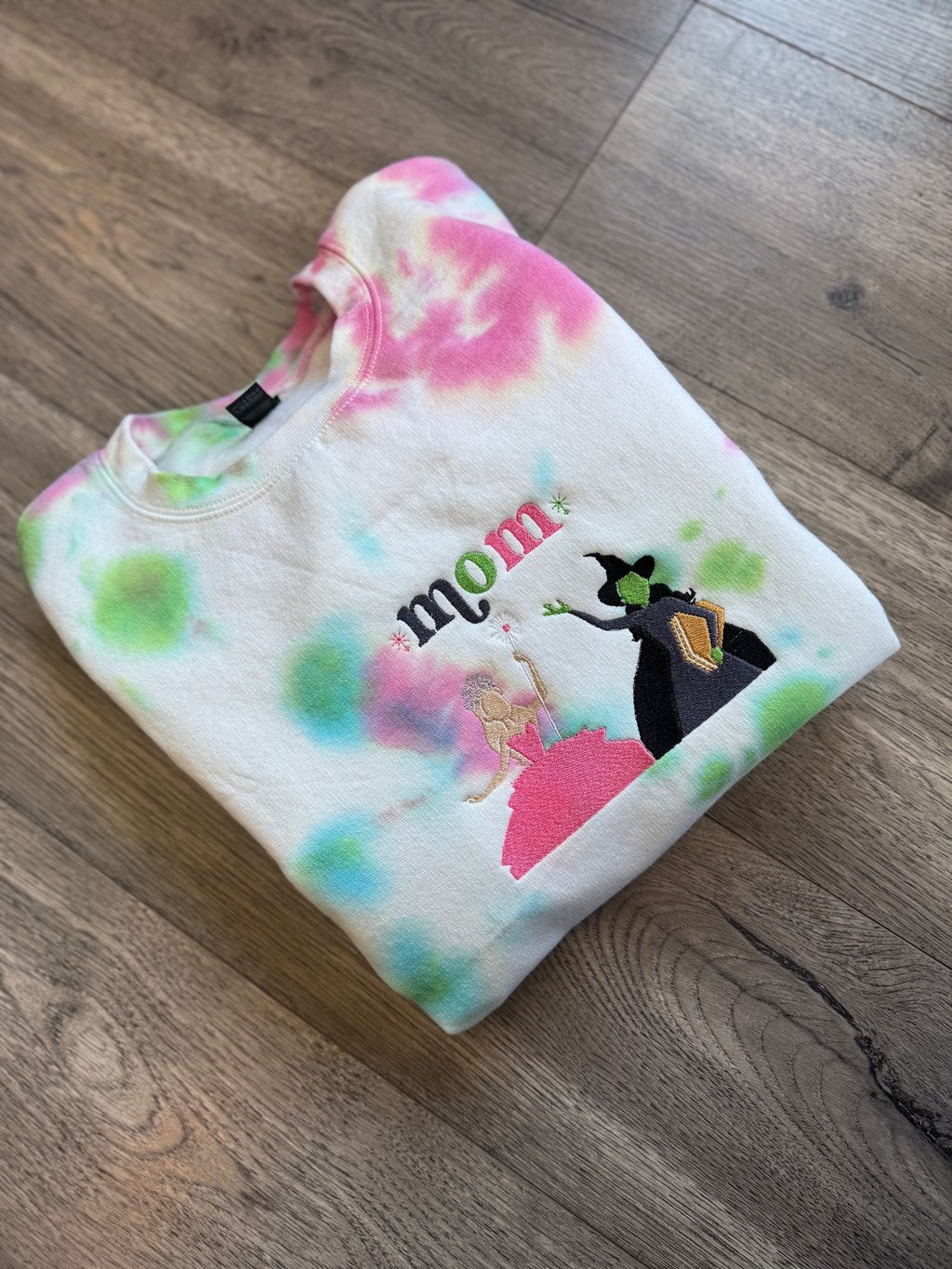 a white, pink and green tie dyed sweatshirt with the word "mom" embroidered on it