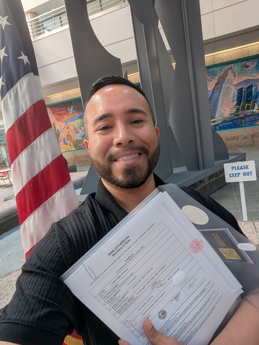 A man holding a certified California apostille document from the Secretary of State next to an American flag.
