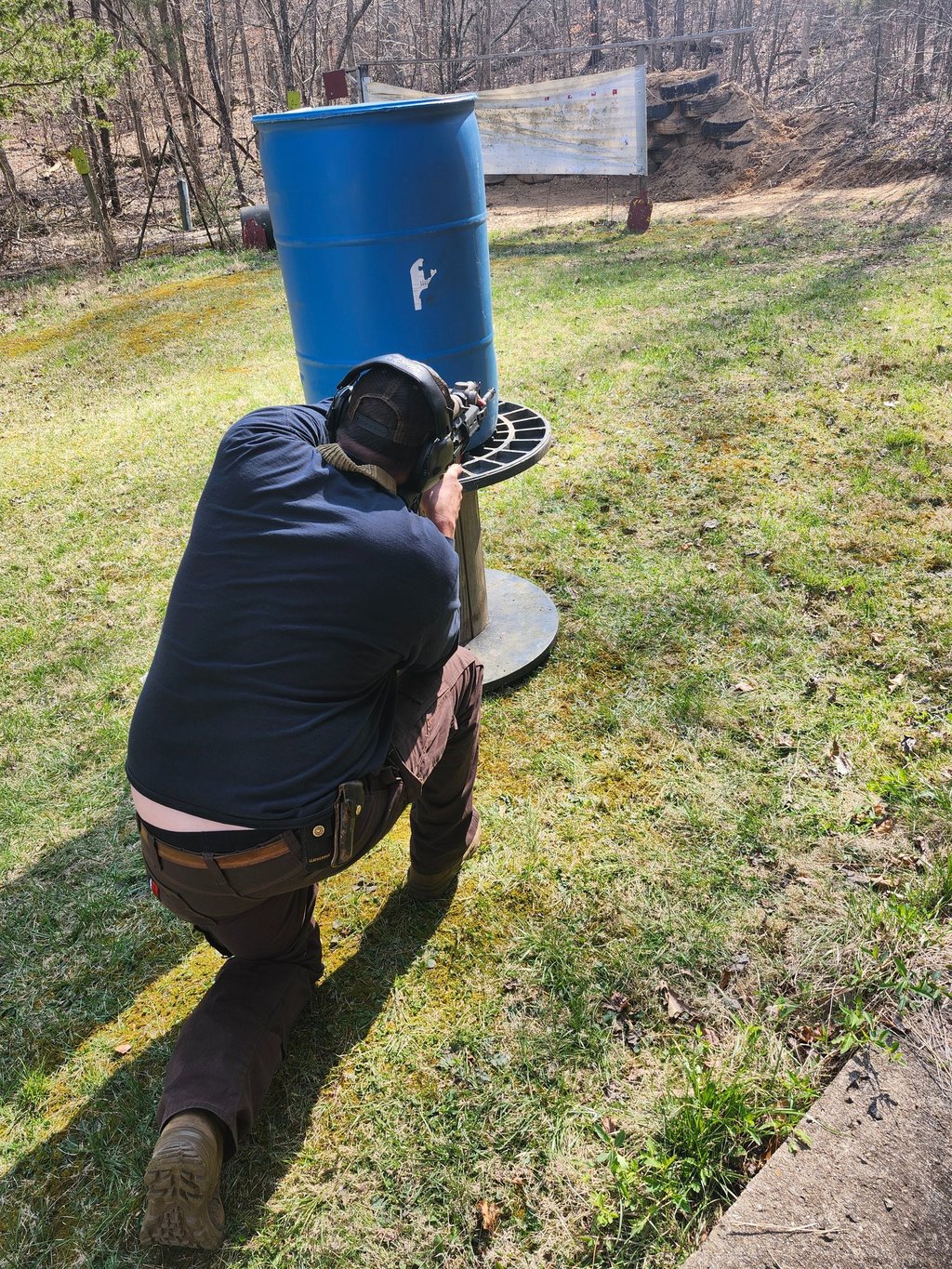 Man using Self-defense firearm (Carbine) kneeling from behind a barrier on training range.