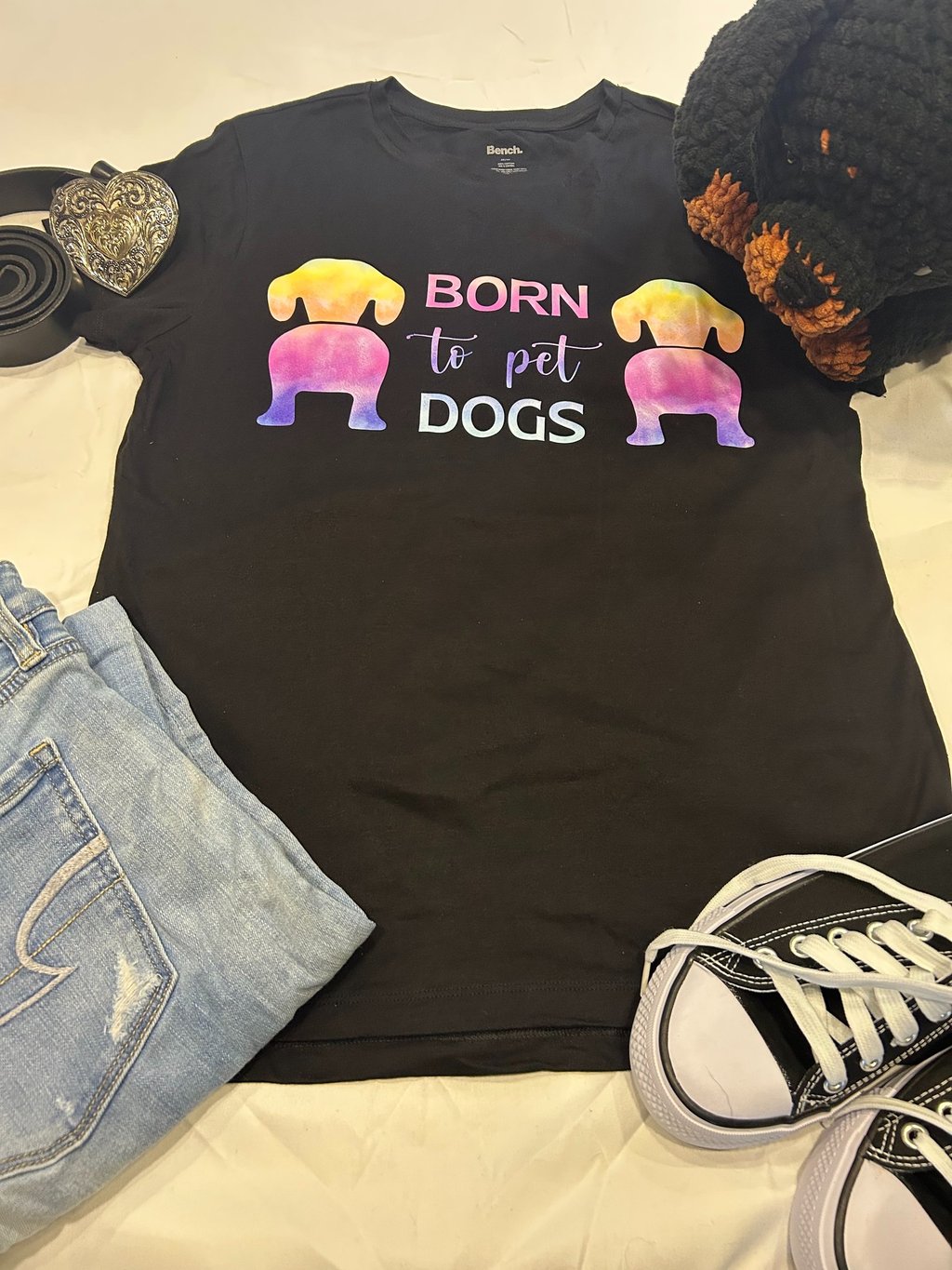a tshirt that says "born to pet dogs" paired with a belt and jeans along with a stuffed rottweiler