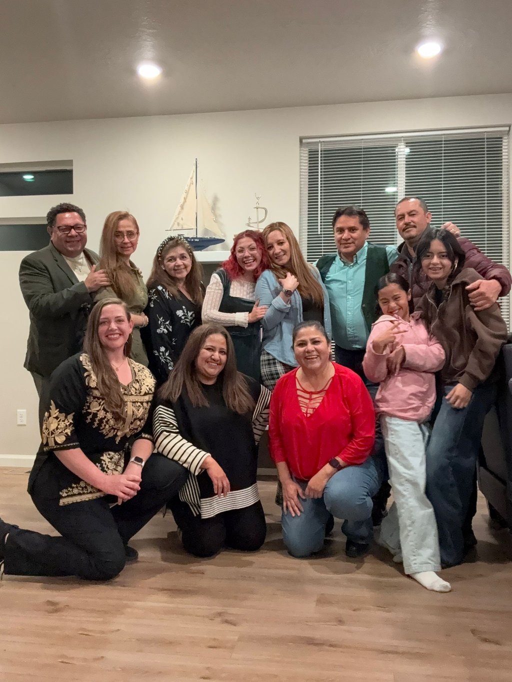 A diverse multi-generational family posing together for a group photo in a living room.