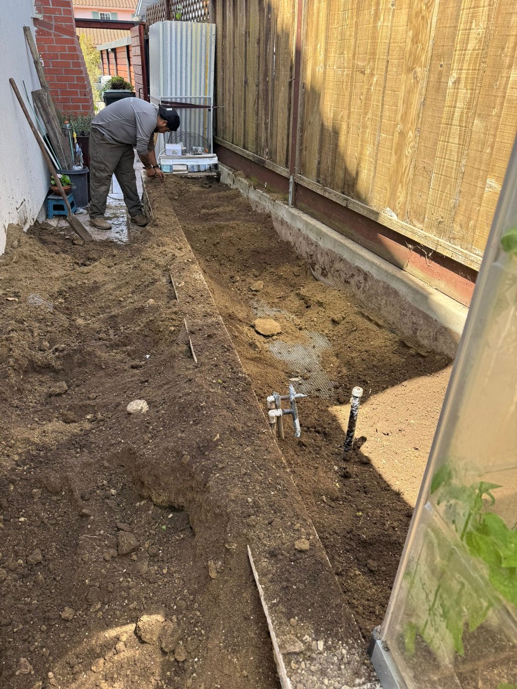 Professional landscaper preparing soil and installing mesh for a residential backyard garden bed in 