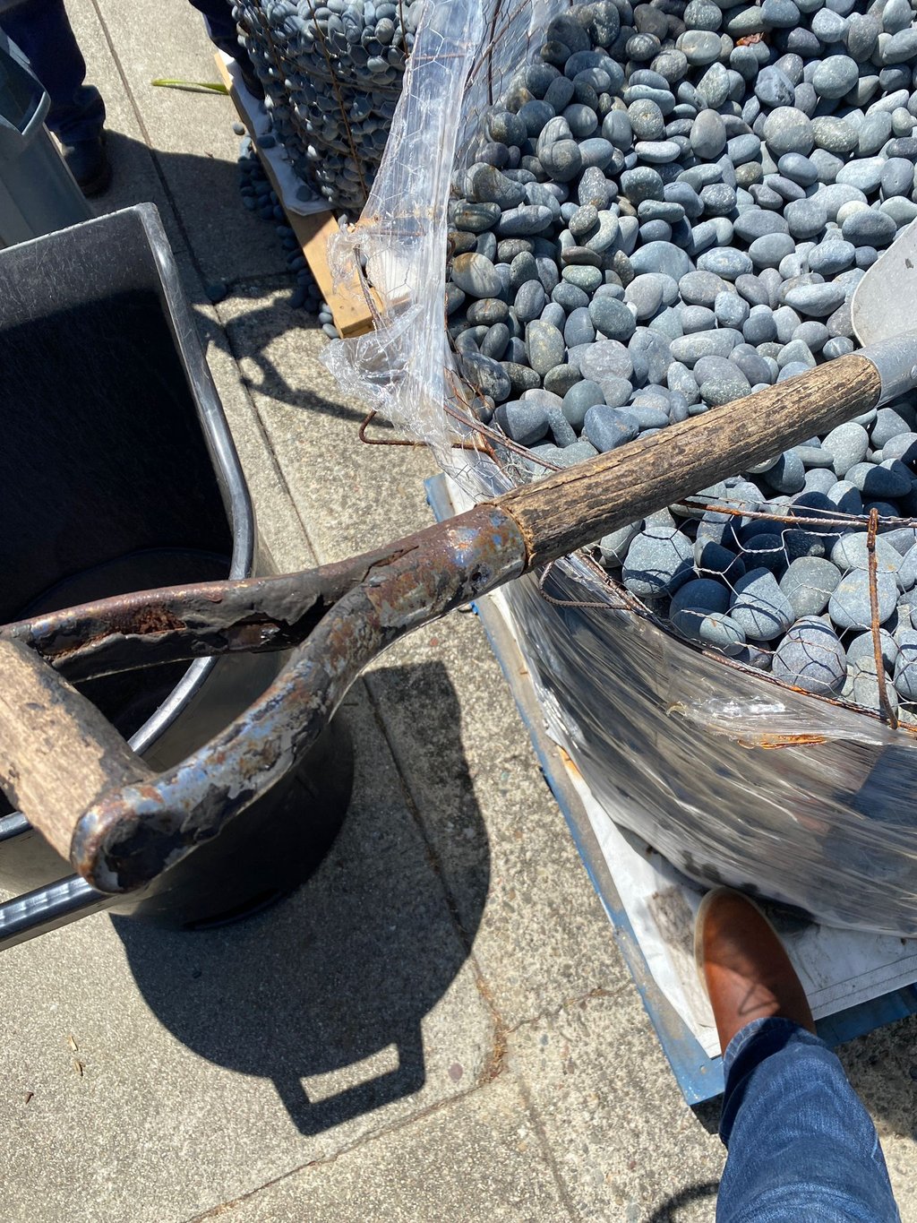 Landscaping San Francisco project showing a worker using a metal garden shovel to place black Mexica