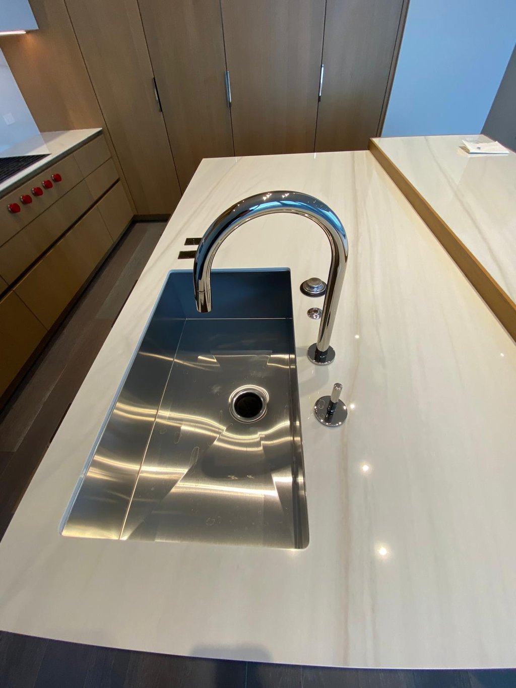 Modern stainless steel undermount kitchen sink on white marble countertop with chrome gooseneck faucet.