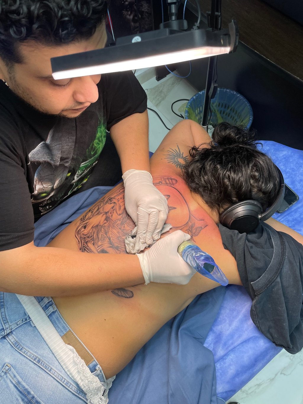 Tattoo artist working on a large back tattoo in a Hurghada tattoo studio 
