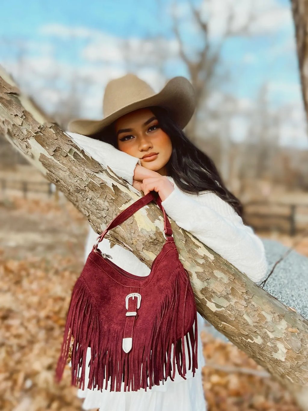 a woman in a white dress and hat with a red fringe purse