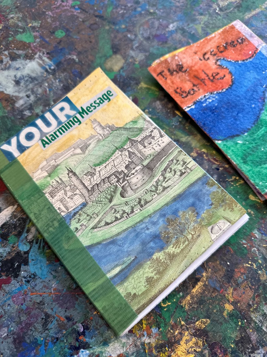 a handmade book with a hand-colored castle and moat on the cover