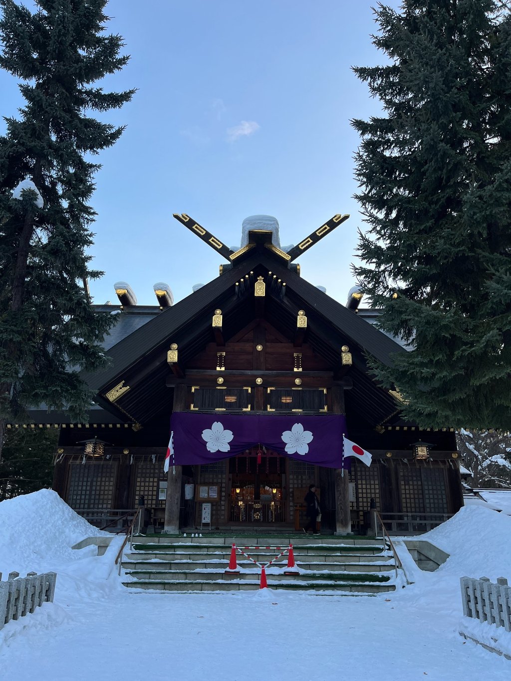 a large wooden building like a temple or sanctuary with a large purple banner in hokkaido japan