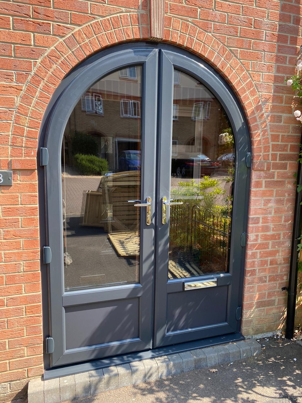 anthracite grey front door with unusual arched shape and reflective glass