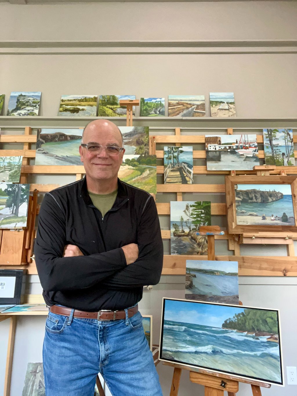Gary McCaslin standing in front of a wall of paintings