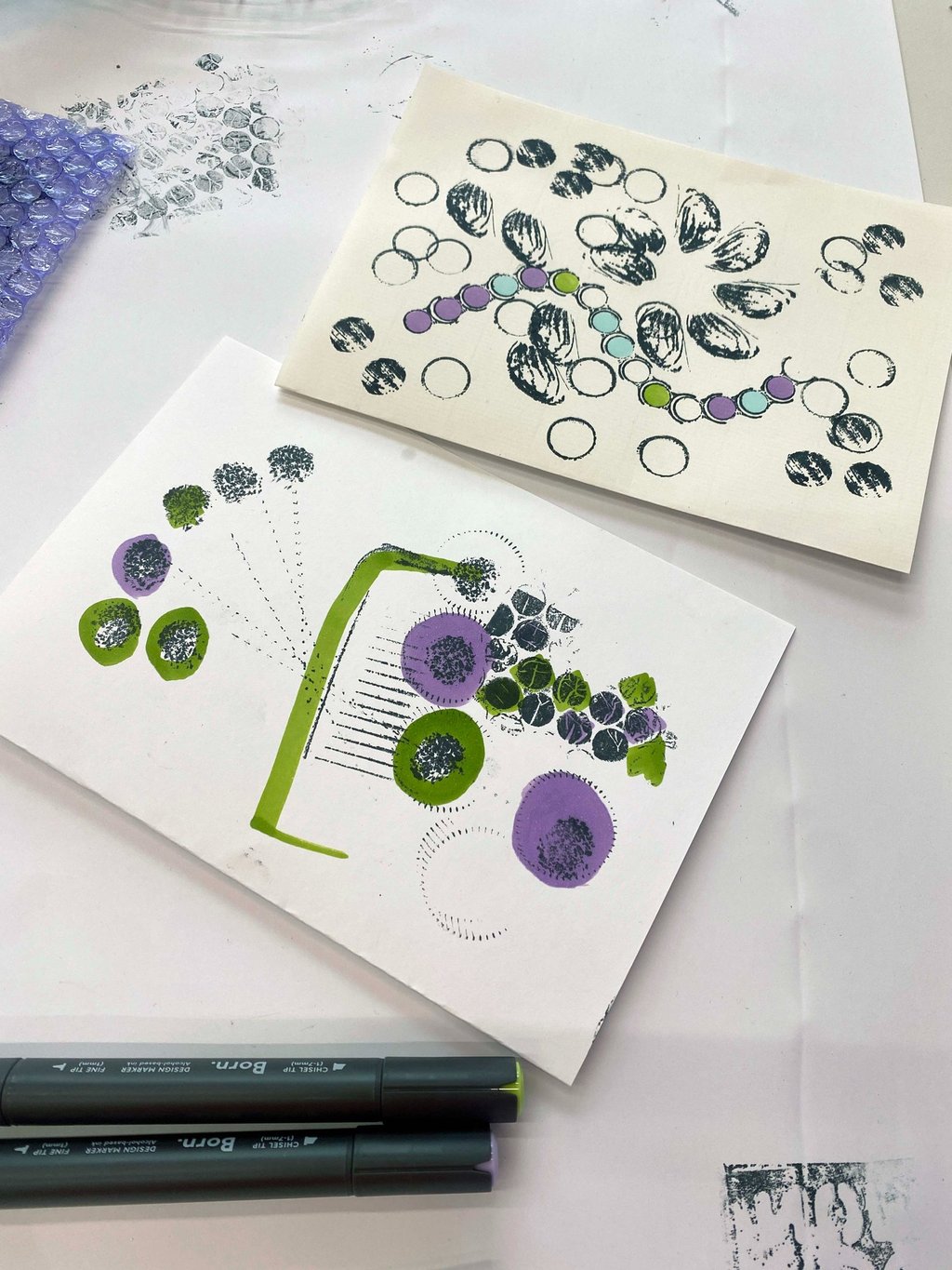 Paper zines with handmade stamps and ink outlines of shapes such as buttons and nut shells.