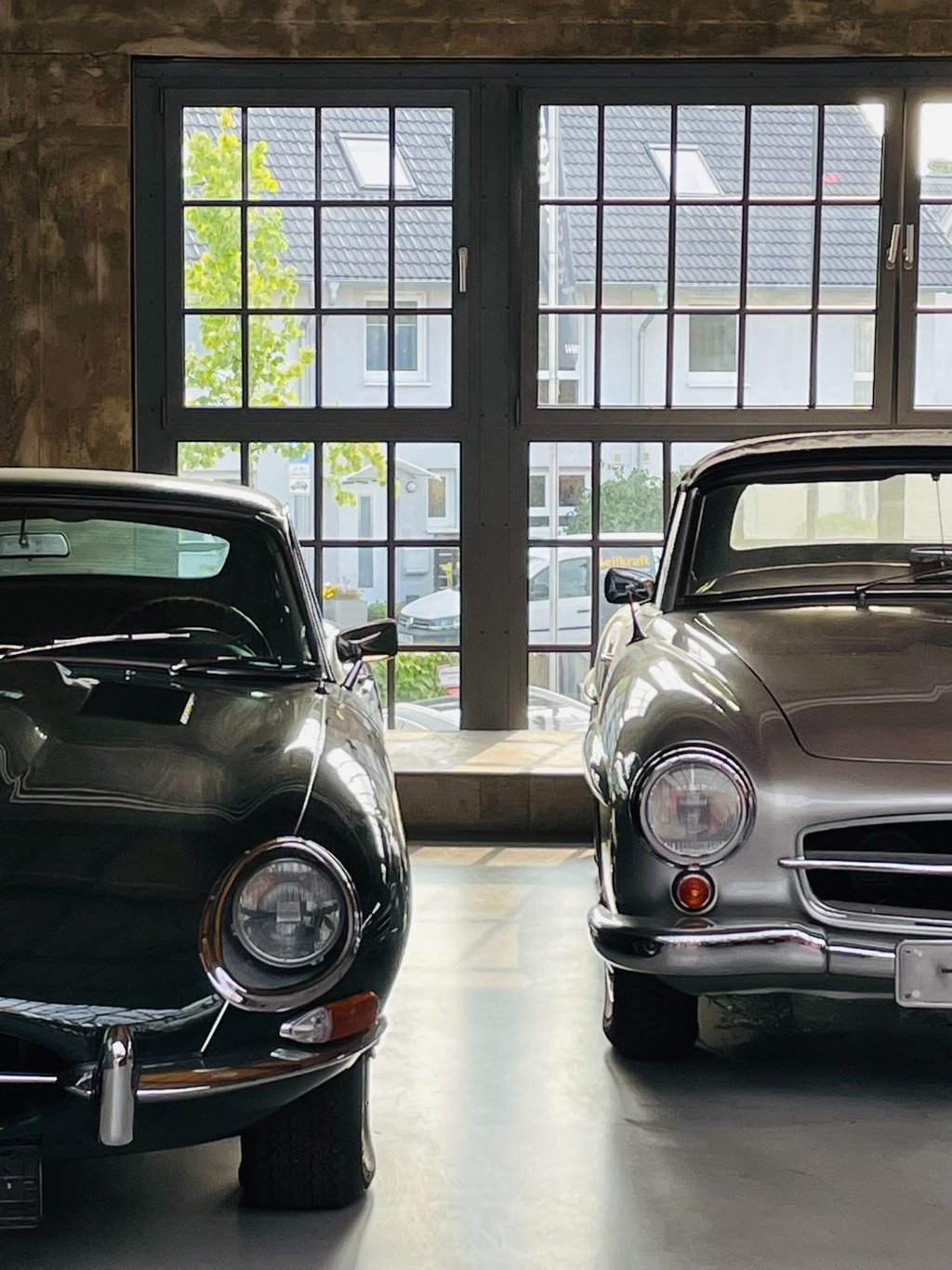 Jaguar & Mercedes Benz sharing stories while parked in a garage
