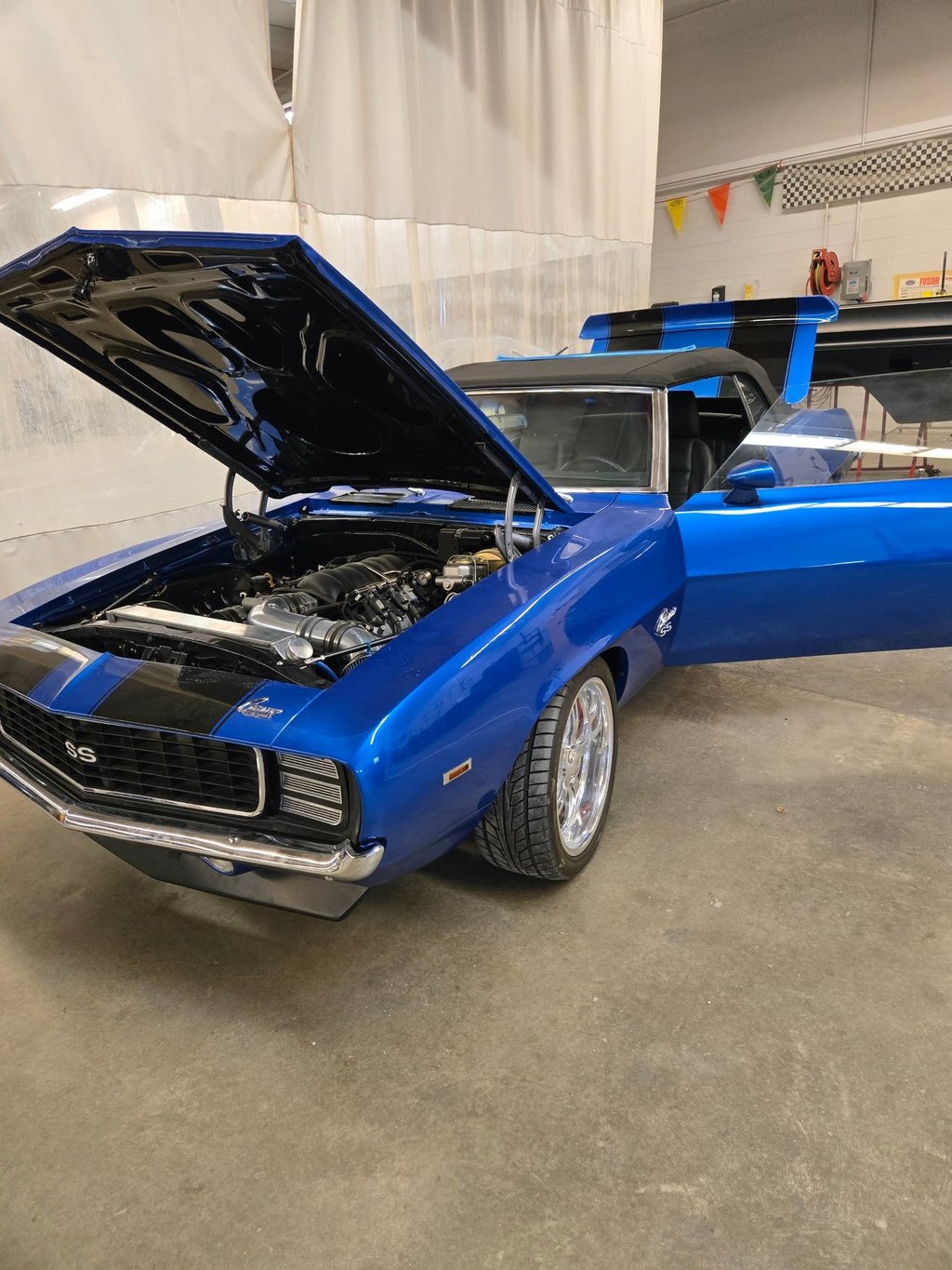 Blue classic classic muscle car with hood open inside a garage