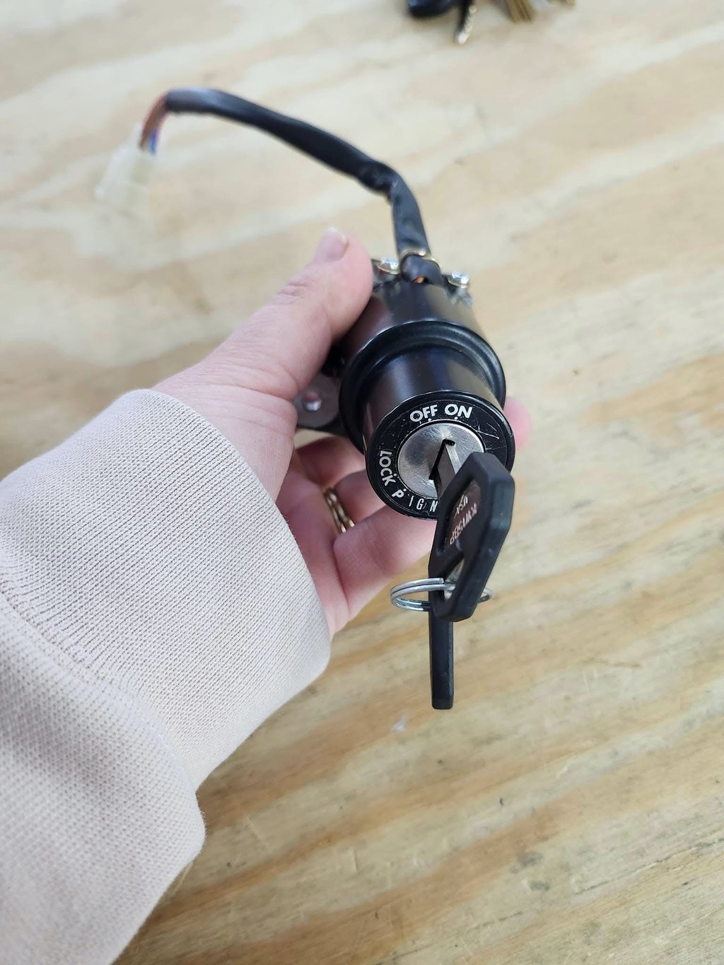 Hand holding a motorcycle ignition cylinder with key inserted