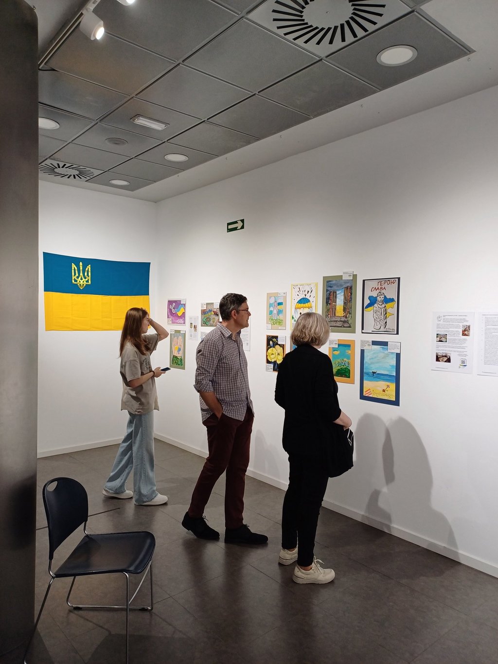 Visitors at the Spanish art gallery with paintings made by kids affected by the war in Ukraine
