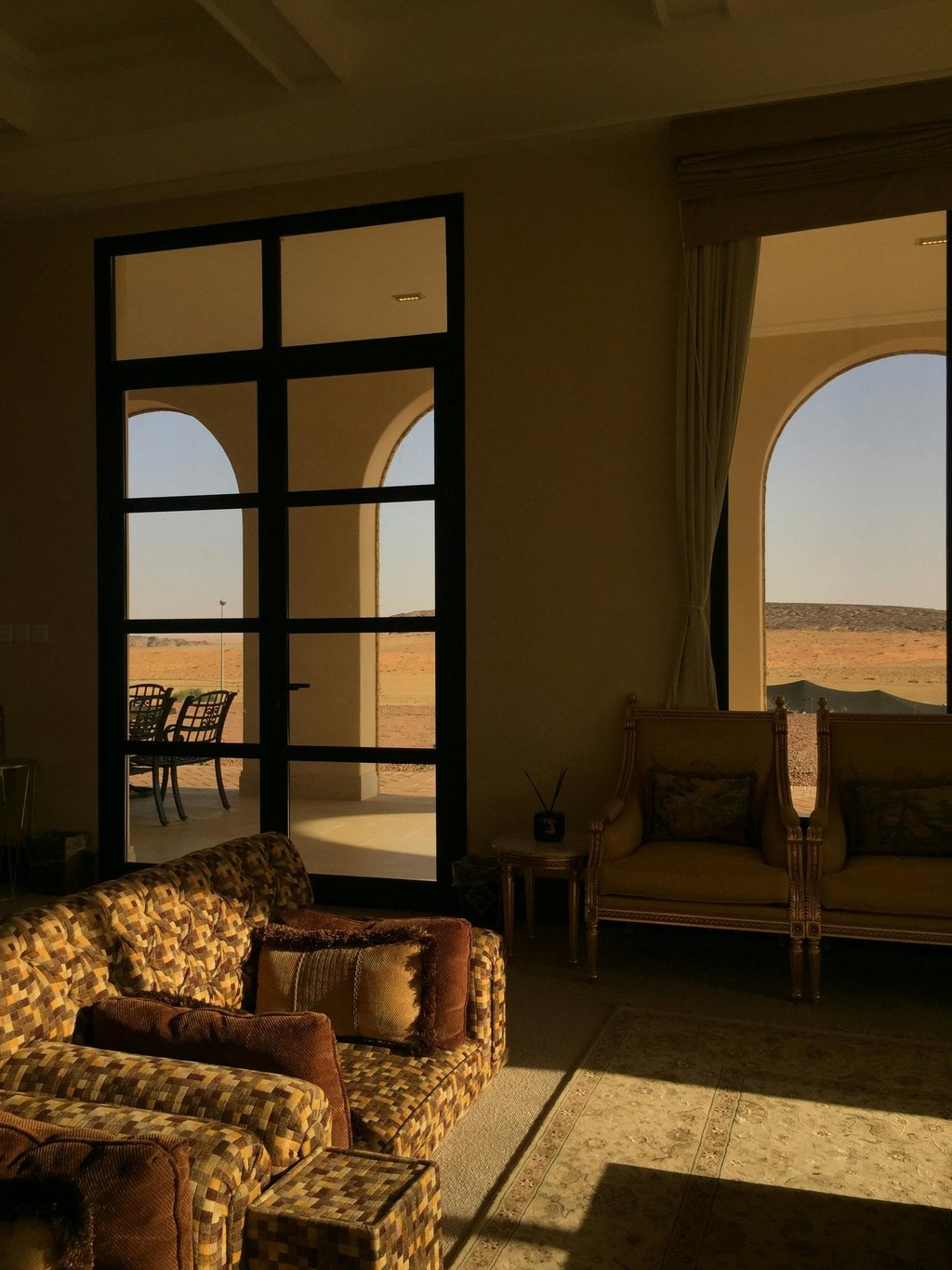 Warm sunlit living room with arched windows and classic lounge seating