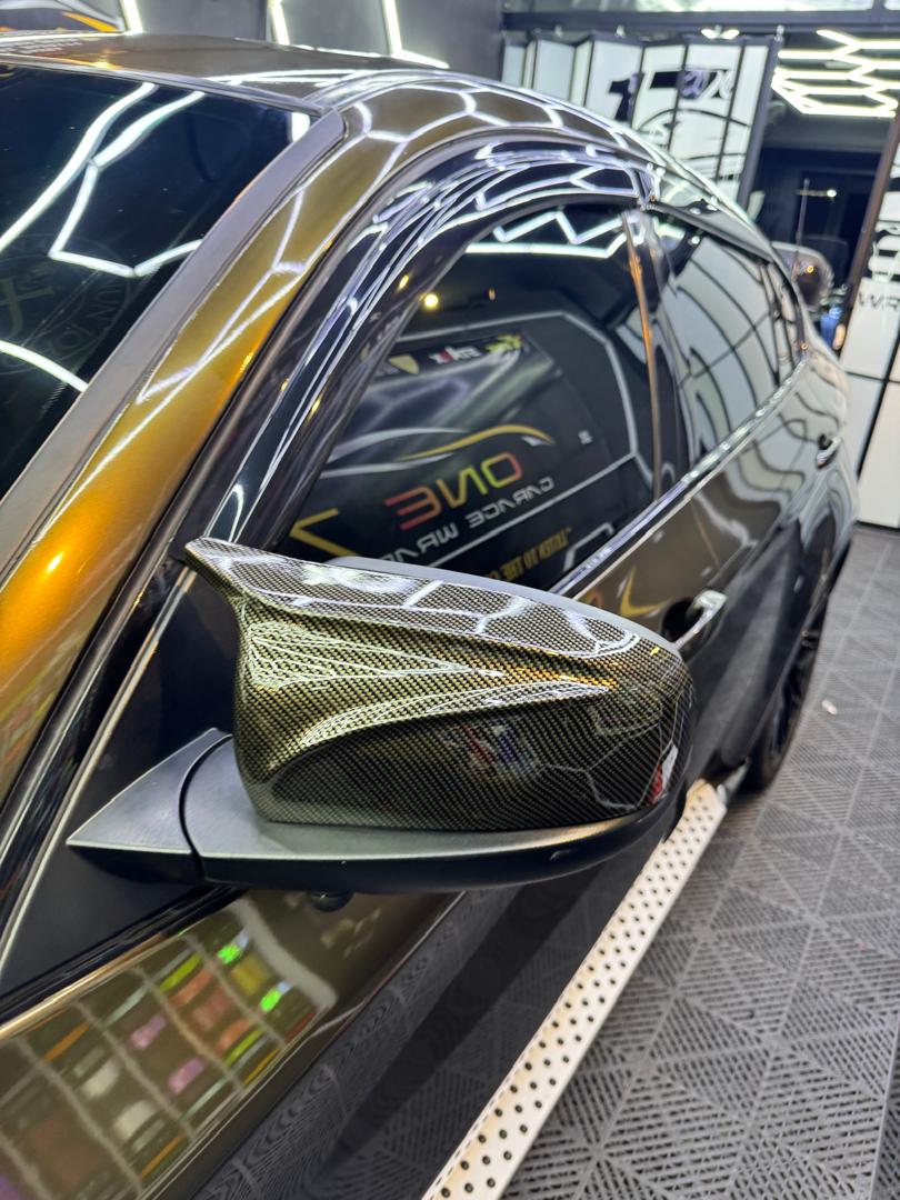 Car side mirror wrapped in carbon fiber vinyl partial wrap