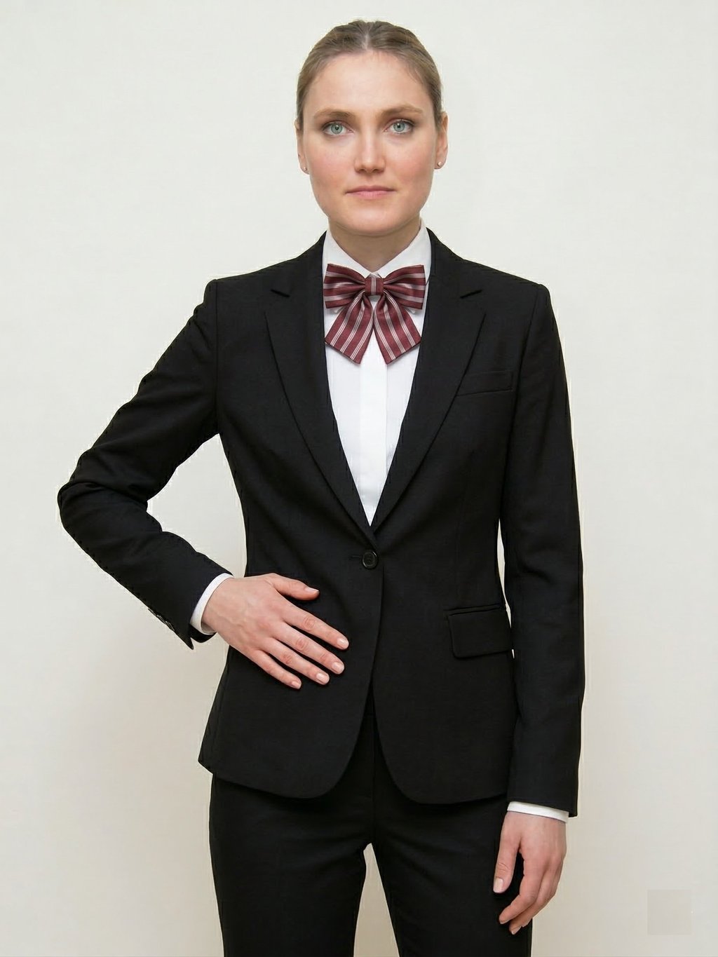 Mujer profesional con un blazer negro a medida y un uniforme con lazo moño de rayas rojas.