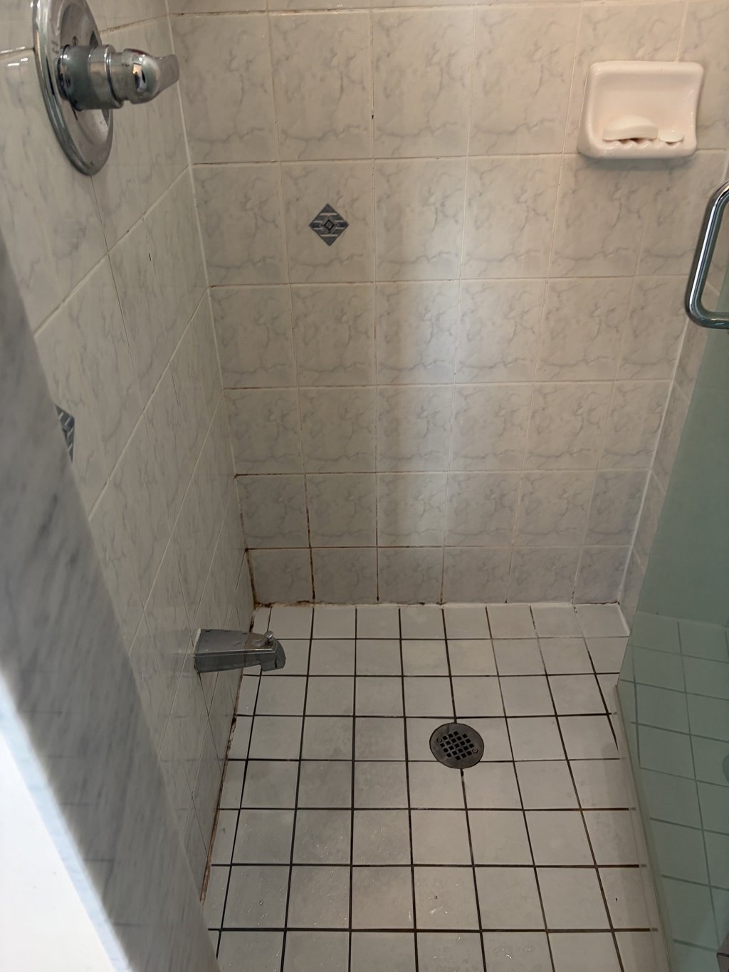 White tiled walk-in shower featuring a faucet, chrome handle, and floor drain for bathroom renovation ideas.