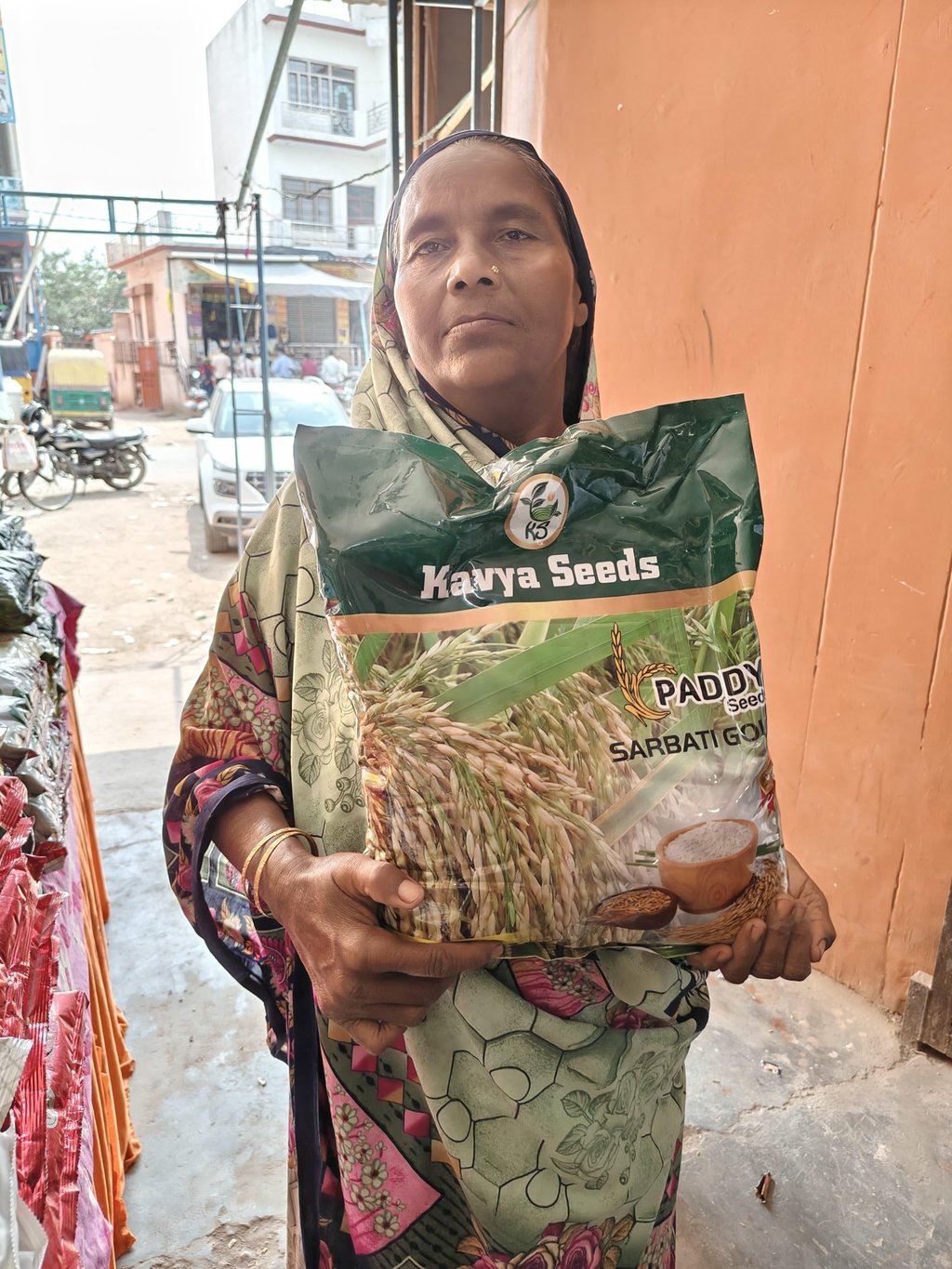 A woman holding a large bag of Kavya Seeds Sarbati Gold paddy seeds for agriculture.