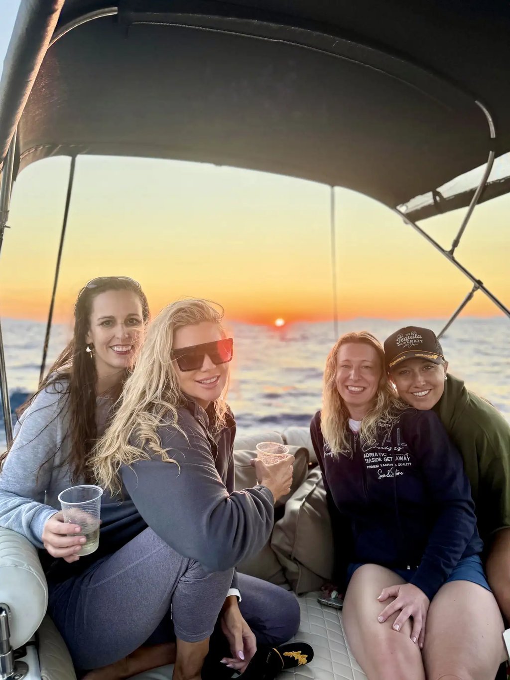 Group of female guests smiling for the camera during a sunset boat tour from Split with the Adriatic sunset in the background