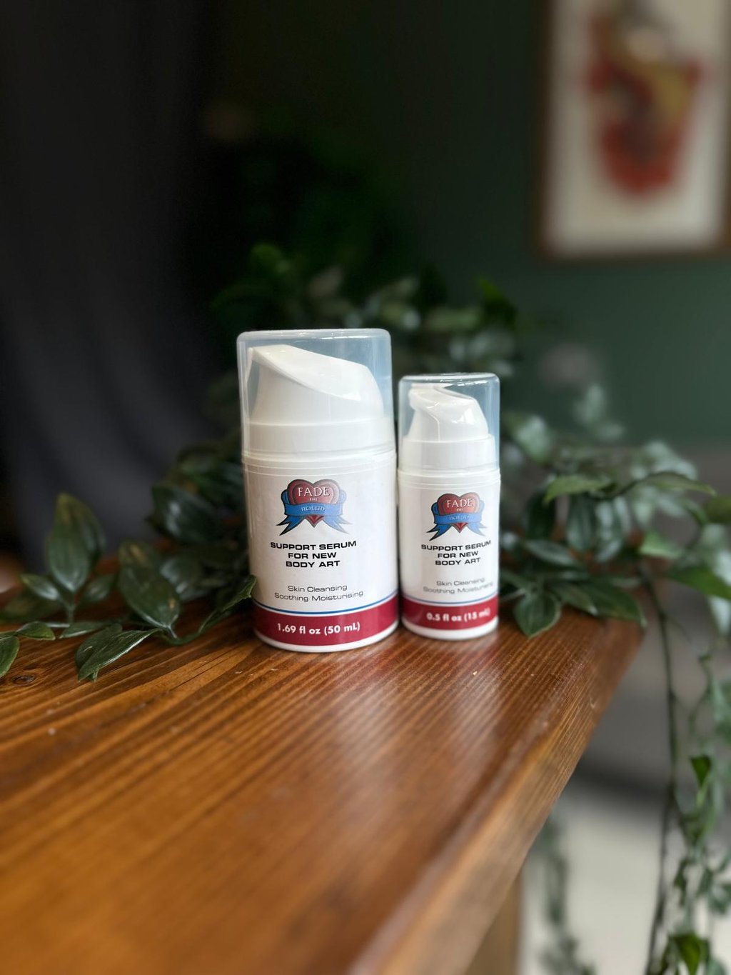 Two bottles of Fade The Heat aftercare support serum for new body art on a wooden table.
