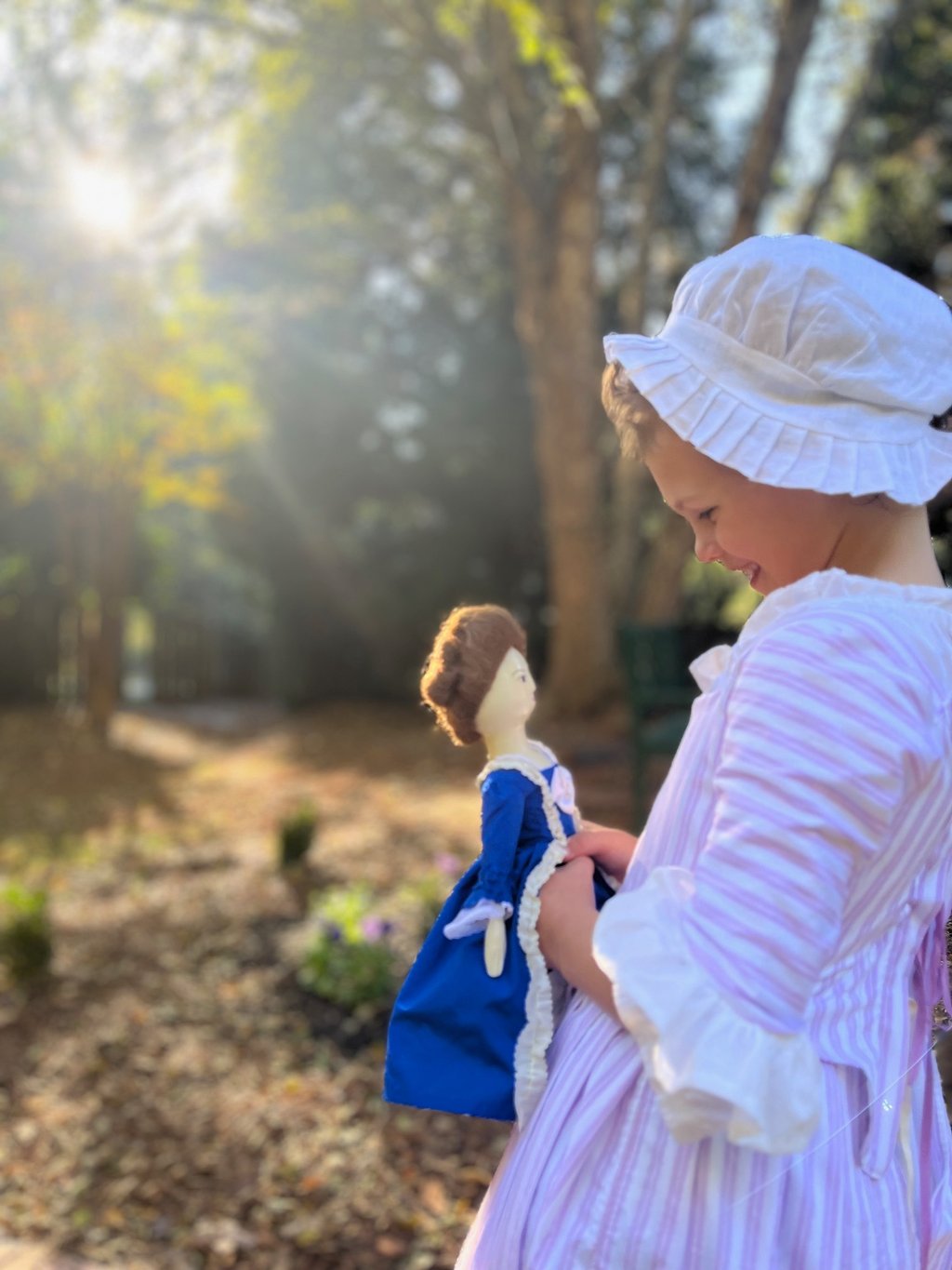 a little girl in a dress and bonnet hat