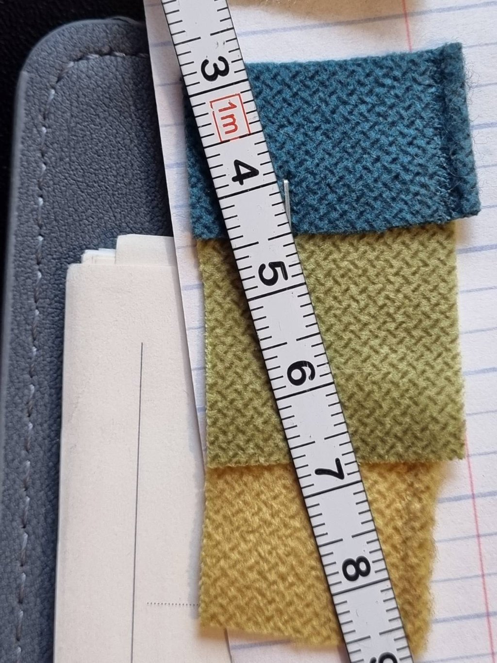 Užuolaidų atkirpti audiniai ir matavimo juosta