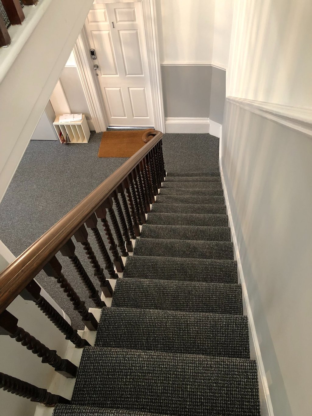 Dark grey carpet runner on stairs with a wooden banister in Worthing. 