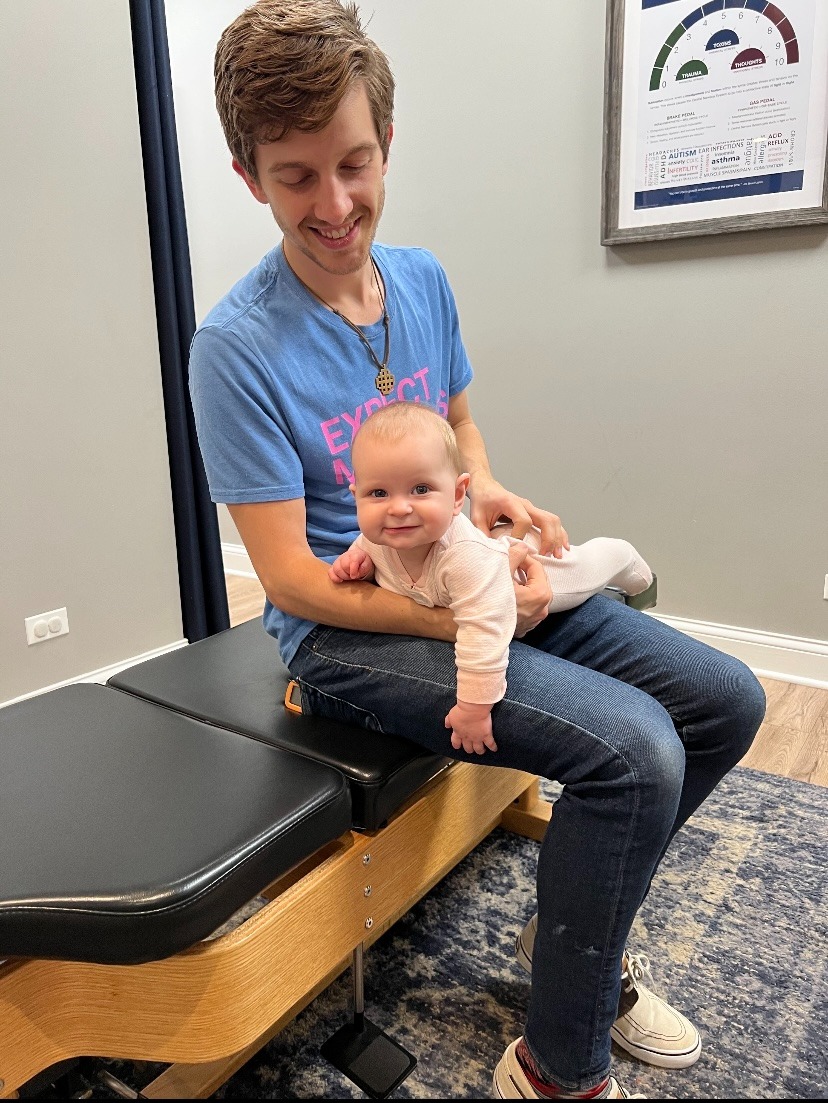 Joyful baby receiving gentle chiropractic care for sleep and digestion