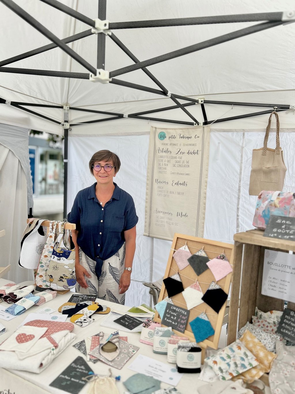 La créatrice derrière son stand sur un marché de créations artisanales