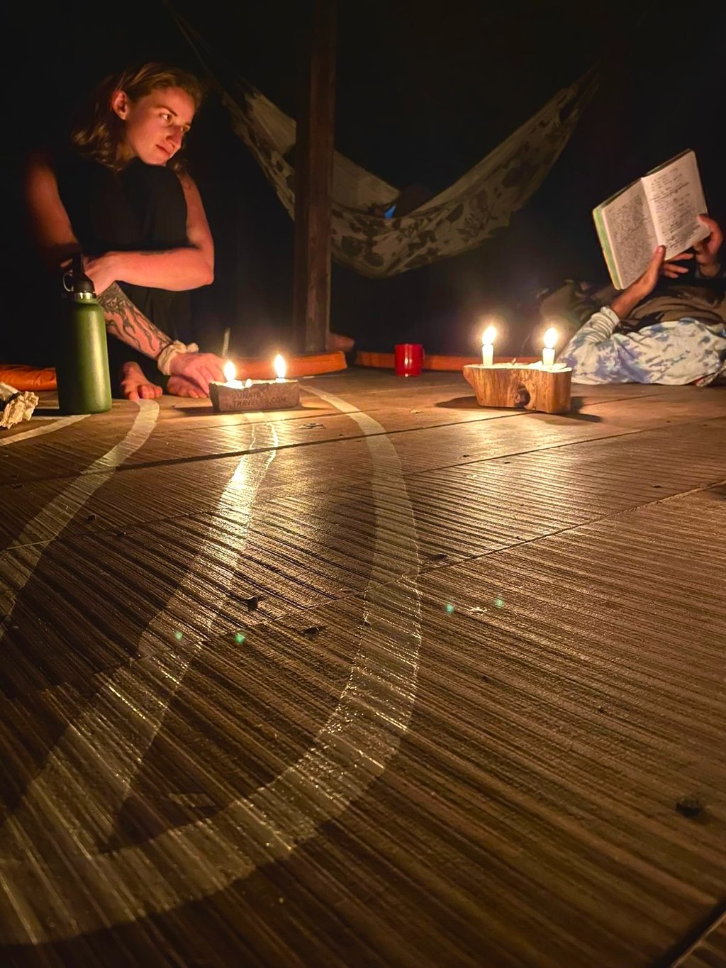 People reading by candlelight on a wooden deck in a bungalow in the Amazon Jungle.