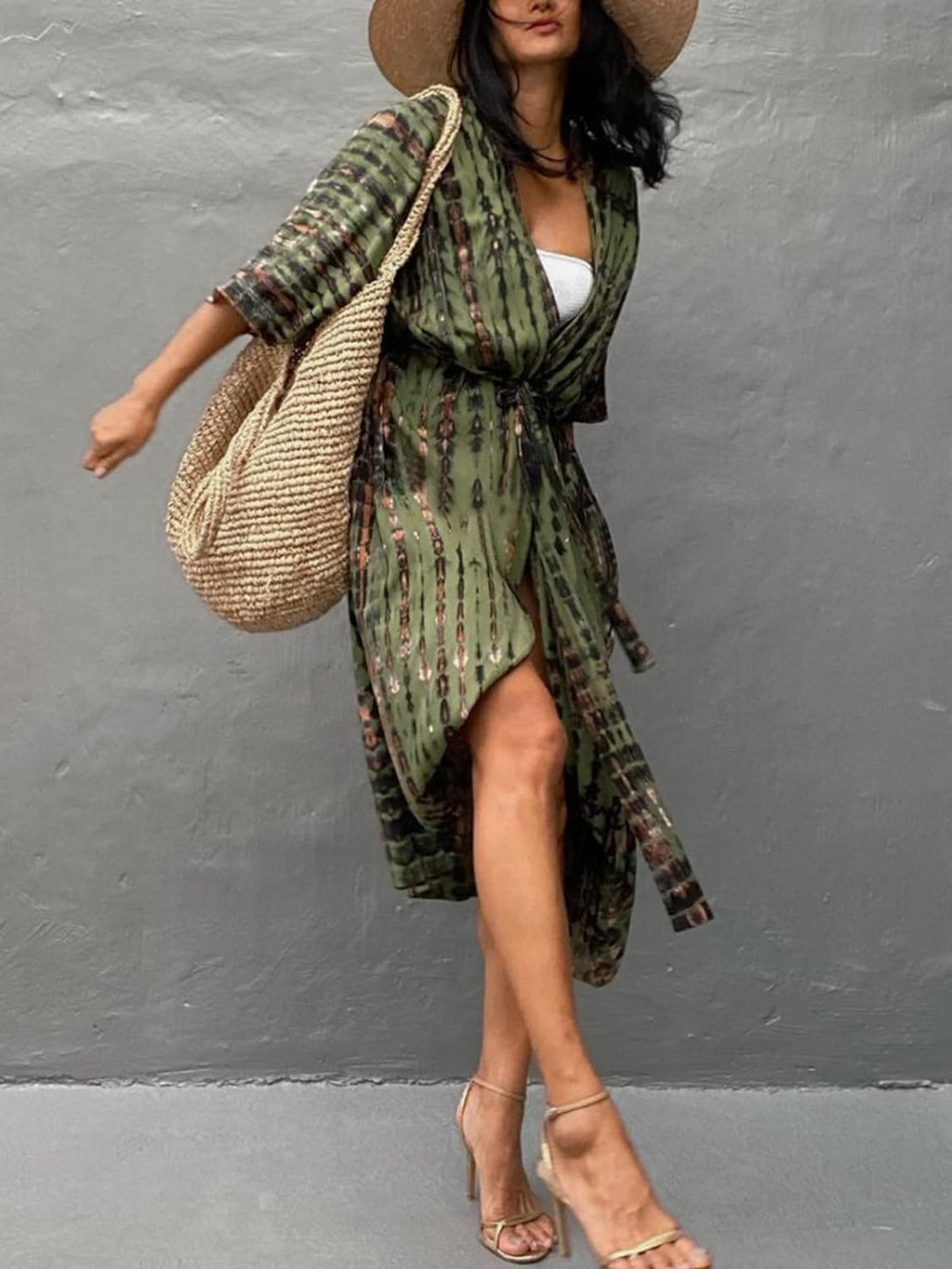 Woman wearing a white croptop underneath a green swuimsuit cover, which is worn as a wrap dress.