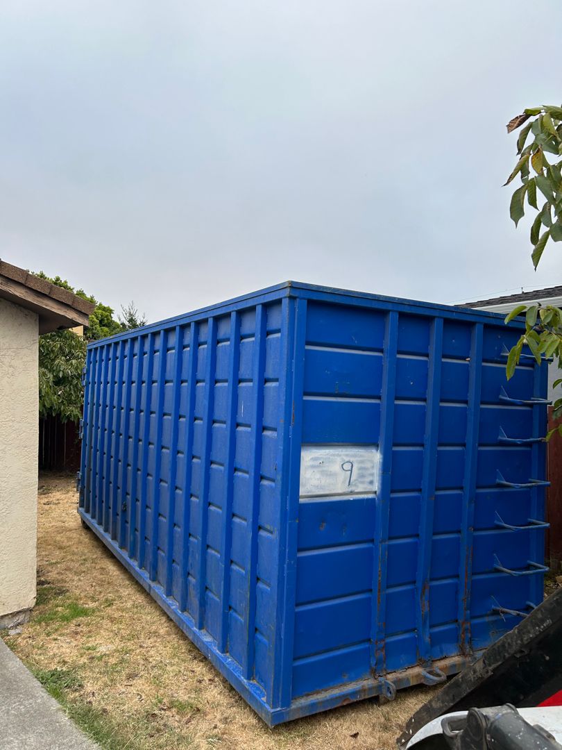 a blue container container sitting on the side of a house