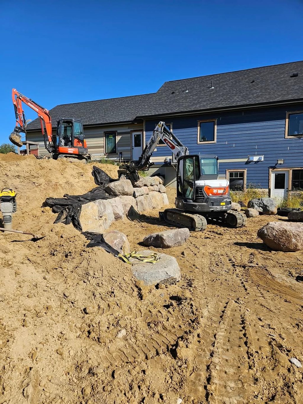 Excavators building boulder wall at residential home in cokato mn