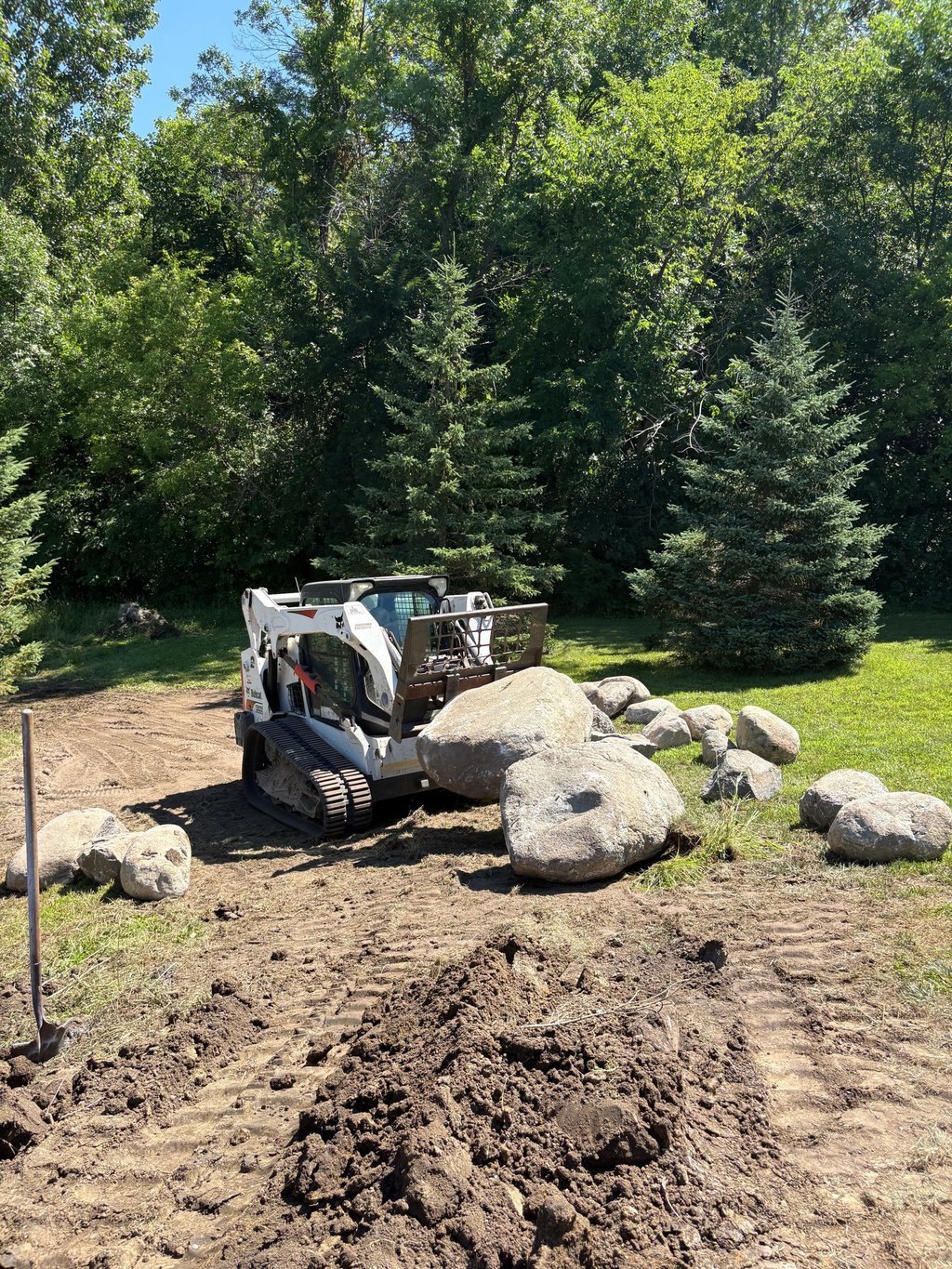 Bobcat skid steer hauling large boulders
