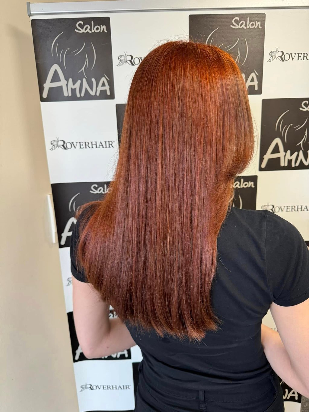 Back view of long, straight auburn red hair styled professionally at Salon Amna.