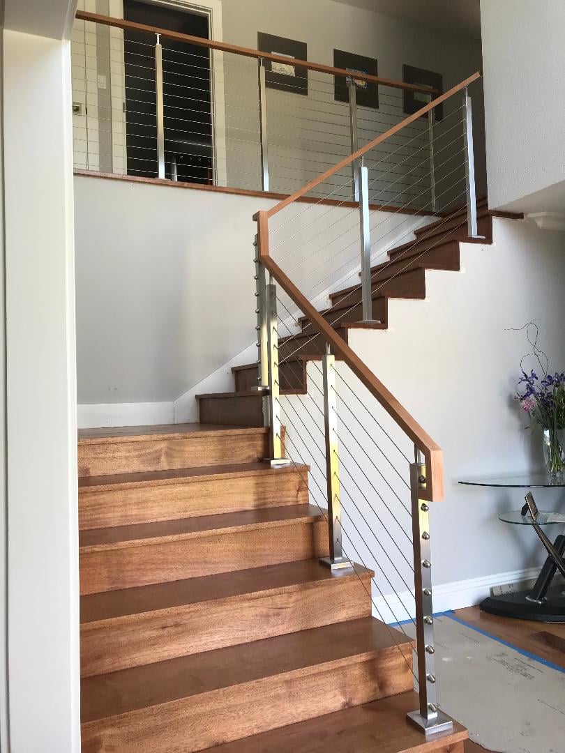 a staircase with a glass railing and a table with a vase of flowers