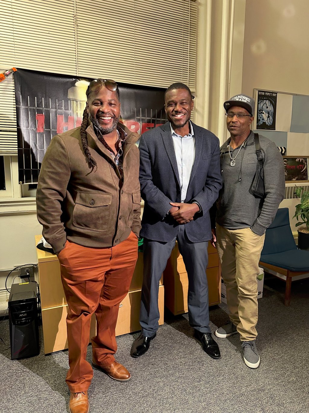 three men standing in a room with a guitar