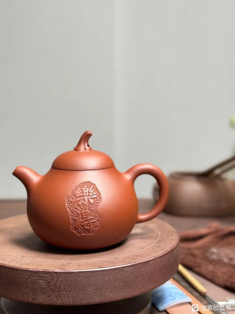 A teapot with engraved text placed on a wooden tabletop