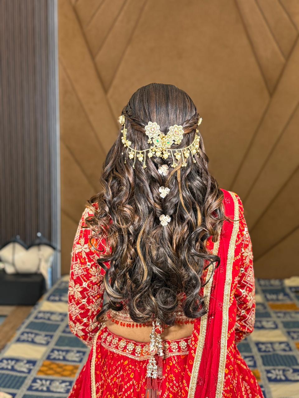Intricate bridal hair weave with floral pins and heavy jewelry for a wedding look in Vadodara.