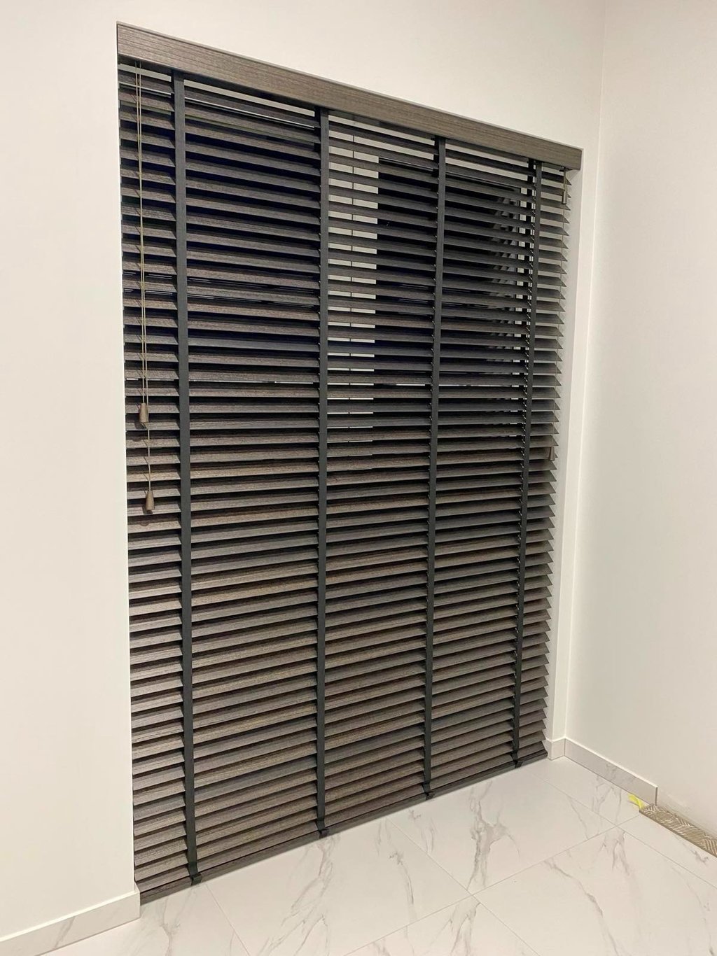 paveikslėlyje atvaizduojama sumontuotos aukštos medinės žaliuzės tamsios spalvos