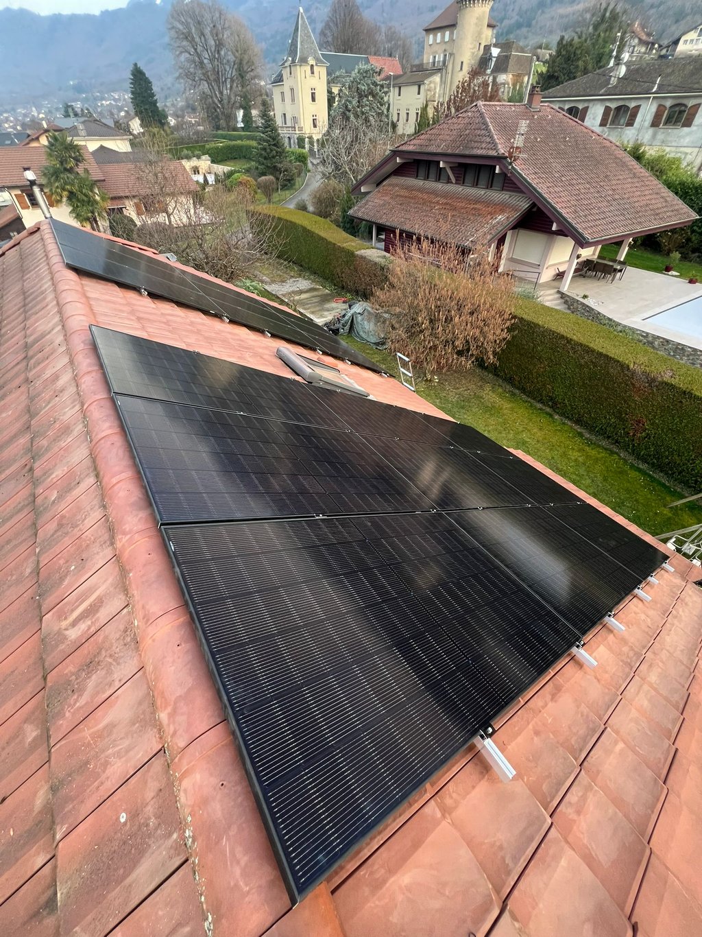 panneaux photovoltaïques installés sur toiture pentue avec vue sur les montagnes près du lac Léman