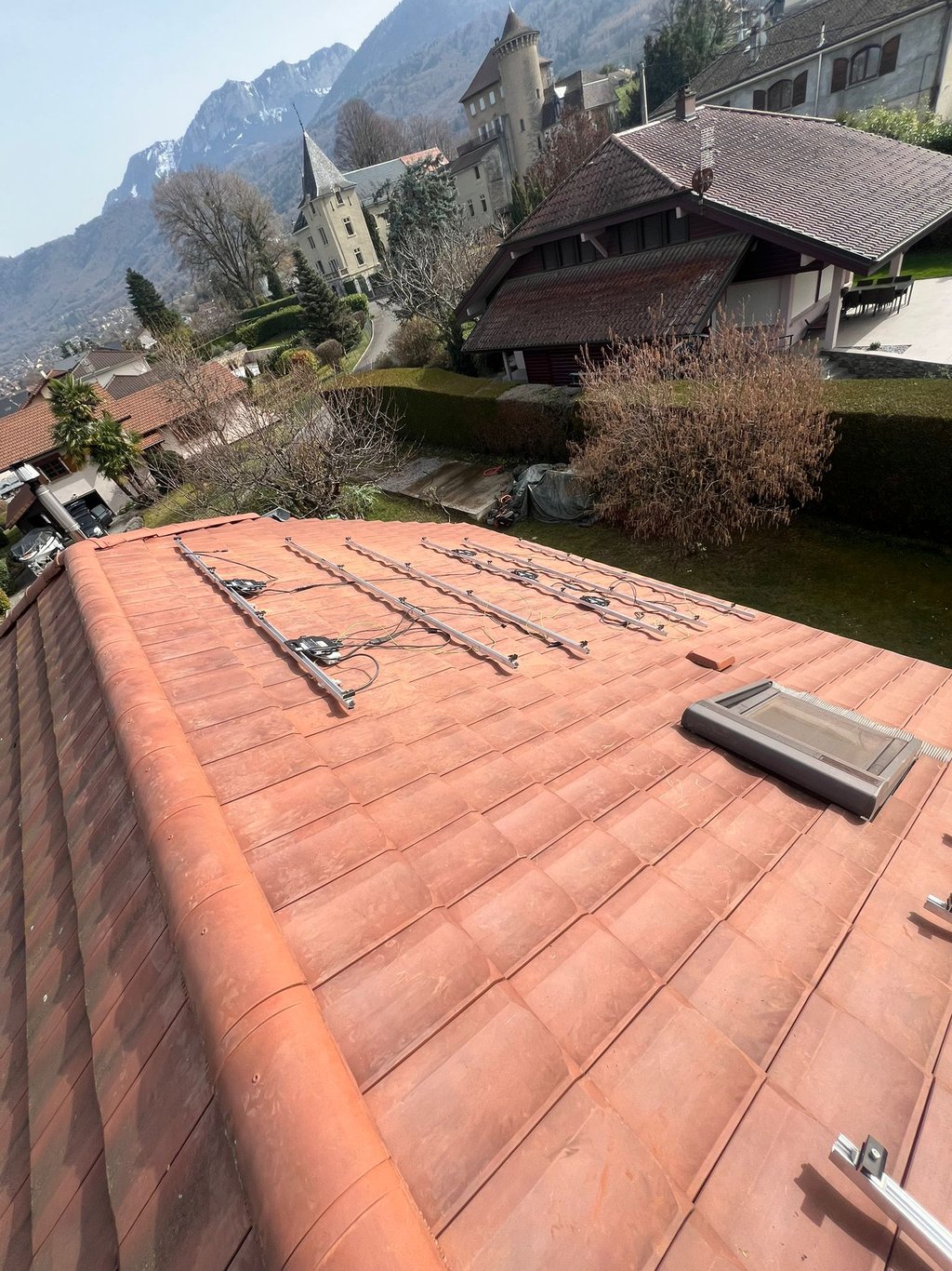 installation des rails et préparation du câblage pour panneaux solaires sur toiture pentue face au lac Léman