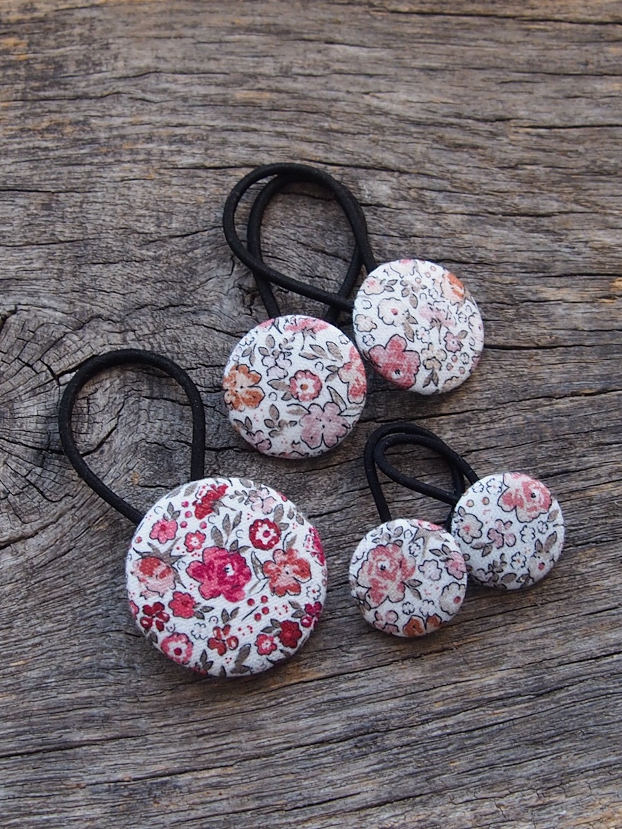 gumki do włosów w kwiaty o różnych wielkościach na tle drewnianej deski