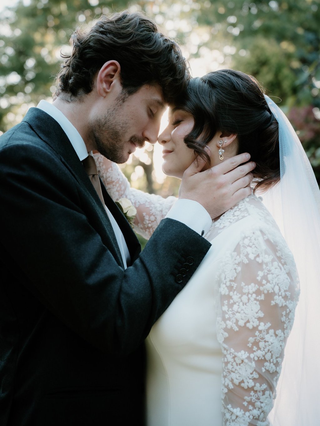 Un marié en costume foncé enlaçant sa mariée dans une robe de mariée en dentelle lors d’une cérémoni